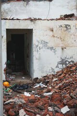 Partially demolished building with yellow hard hat visible among the broken bricks and debris in urban Southeast Asia