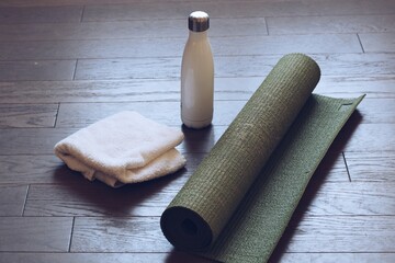 Yoga mat, water bottle and a fresh white towel ready for a home workout