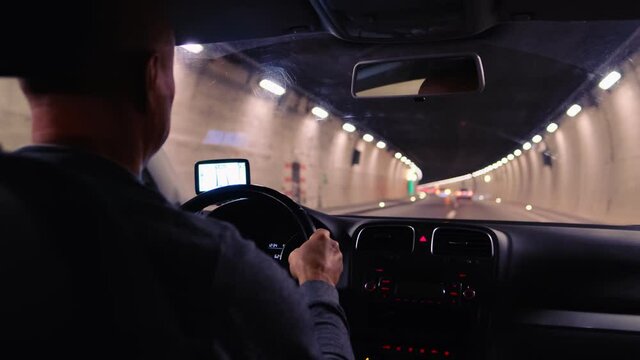 car driver driving through a long, lamp-lit tunnel in the Swiss mountains, selective focus on the vehicle dashboard, auto travel concept, road traffic, positive exit