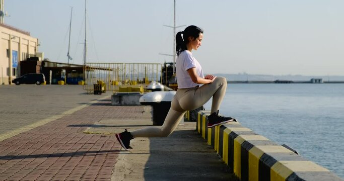 girl crouches lunges on the dock, in the background the sea and ships. sexy ass