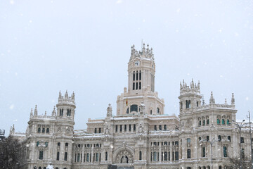Fototapeta na wymiar Madrid center with the monument of the city hall in the background while snowing - winter postcard from Spain