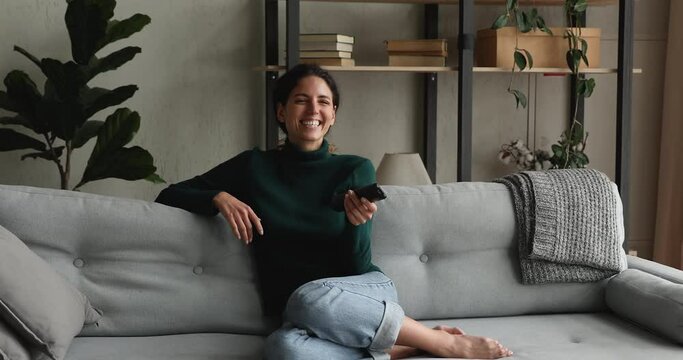 Woman switching channels relaxing on comfy couch in living room alone, choose comedy film for funny pastime, watching entertaining programs reality show series on tv. Leisure, smart television concept