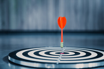 Dart arrow hit on bulleyes of dartboard to represent that the business reached the target  with...