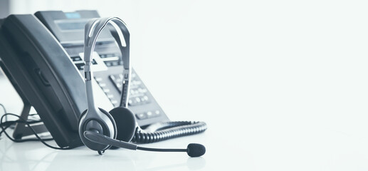 Communication support, call center and customer service help desk. VOIP headset on telephone keyboard.