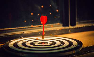 Dart arrow hit on bulleyes of dartboard to represent that the business reached the target  with...