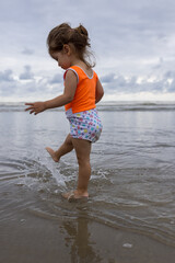 Fototapeta na wymiar menina sorridente e feliz brincando na beira do Mar