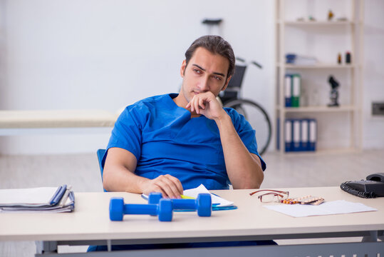 Young male doctor physiotherapist doing sport exercises
