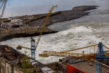 Naklejka premium Water discharge on the Kolyma river against the background of a domba under construction