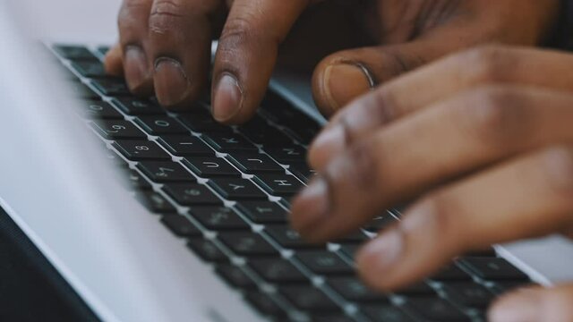 Close up, hands of a black man typing on the laptop keyboard. remote work concet. High quality 4k footage