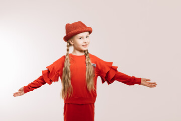 Little girl in a red suit and hat posing on a light background