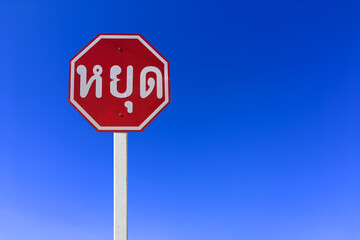 Isolated Stop sign on pole with clipping paths. Thai language in the photo means "Stop" in English.