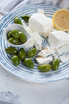 Close-up Of Giant Green Olives And Blocks Of Feta Cheese On A Blue And White Plate, Vertical Shot, Selective Focus