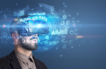 Businessman looking through Virtual Reality glasses with BIG DATA inscription, innovative technology concept