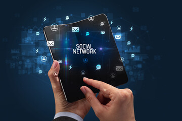 Businessman holding a foldable smartphone with SOCIAL NETWORK inscription, social networking concept
