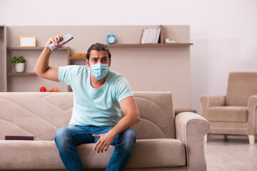 Young man watching tv at home during pandemic
