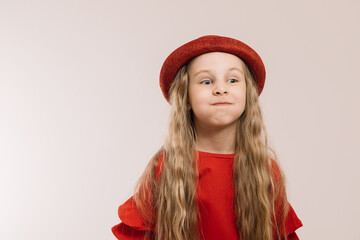 Little girl in a red suit and hat posing on a light background