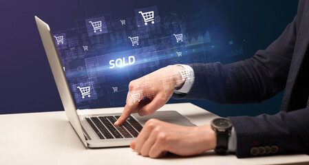 Obraz na płótnie Canvas Businessman working on laptop with SOLD inscription, online shopping concept