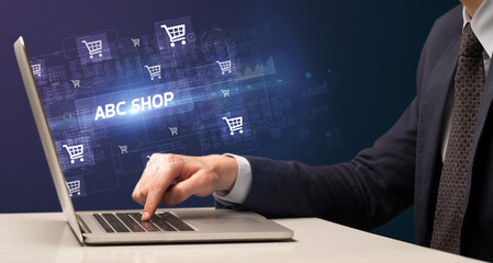 Businessman working on laptop with ABC SHOP inscription, online shopping concept