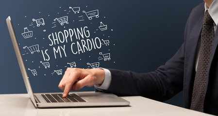 Businessman working on laptop with SHOPPING IS MY CARDIO inscription, online shopping concept