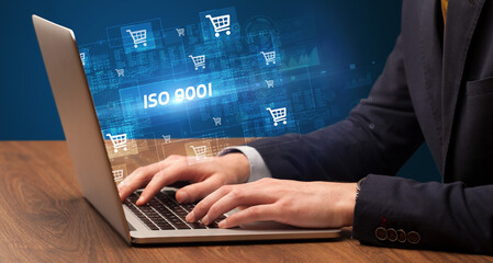 Businessman working on laptop with ISO 9001 inscription, online shopping concept