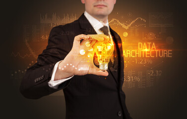 Businessman holding lightbulb with DATA ARCHITECTURE inscription, Business technology concept