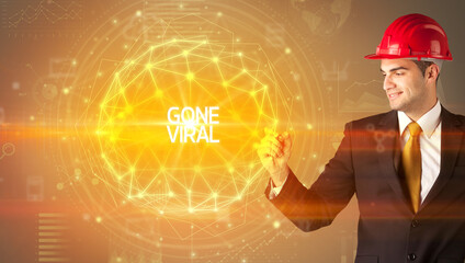 Handsome businessman with helmet drawing GONE VIRAL inscription, social construction concept