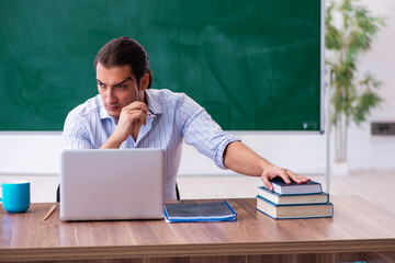 Young male teacher in front of blackboard