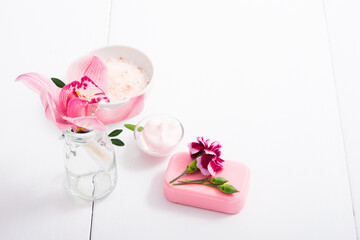 cosmetic cream, soap and bath salt with pink flower, white wood table