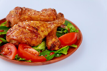 Baked spicy chicken drumstick with salad on white background.