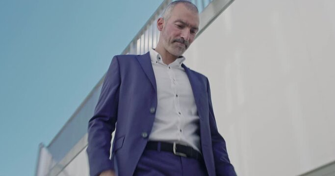 Handsome professional Business man in a suit walking running down stairs in modern building environment front on angle