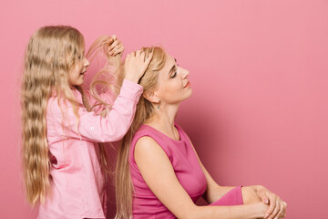 mother with daughter in pink clothes on a pink background