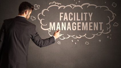 businessman drawing a cloud with FACILITY MANAGEMENT inscription inside, modern business concept