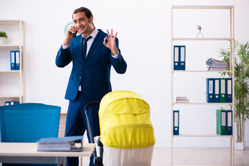 Young male employee looking after kid at workplace