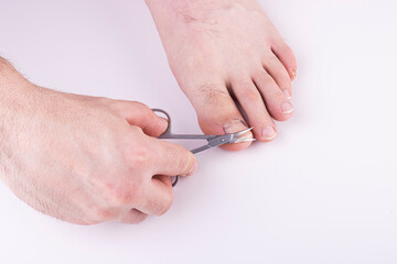 men's hands cut their toenails with scissors on a white background