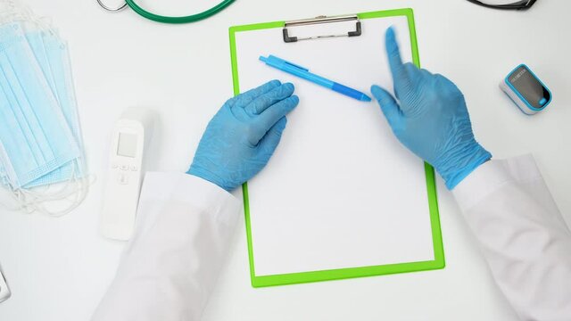 doctor in a white coat and blue latex gloves gesturing with his hands while sitting at a white work table, top view, conversation