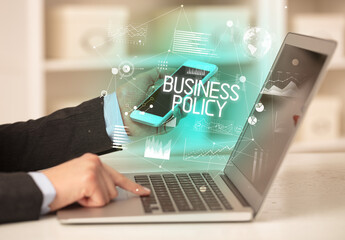 Side view of a business person working on laptop with BUSINESS POLICY inscription, modern business concept