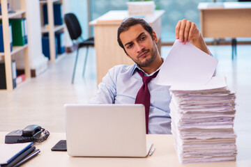 Young male employee unhappy with excessive work in the office