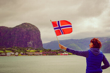 Tourist with norwegian flag on fjord