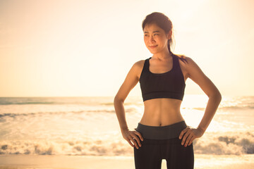 Fototapeta na wymiar Young Asian athletic muscle woman standing and warmup for running on beach in morning or evening 