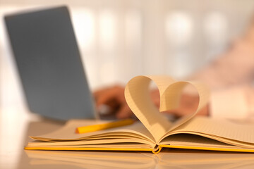 Close up heart shape from paper book on table. Yellow notebook. Valentine day.