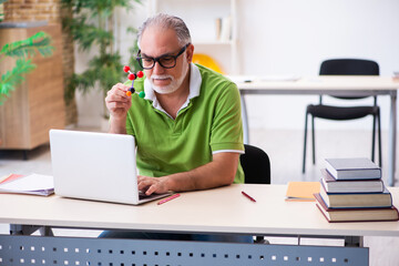 Old male student physicist studying molecular model