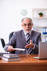 Obraz premium Old male businessman employee reading contract in the office