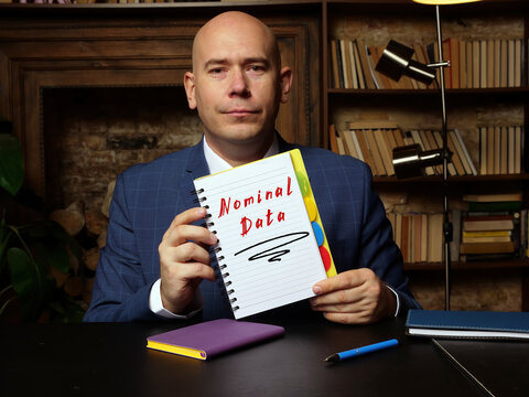 Business man holding white notepad with written text Nominal Data - closeup shot.