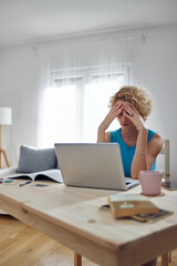 Woman working from home and being depressed, tired with headache. Modern concept and problems with freelancers.