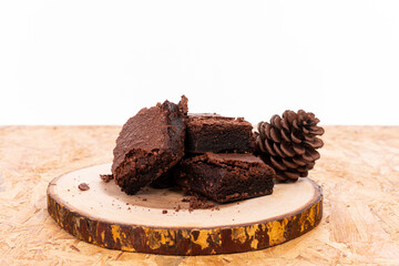 Pieces of fresh chocolate brownie on wooden plate on white background. Stack of fudgy chocolate...