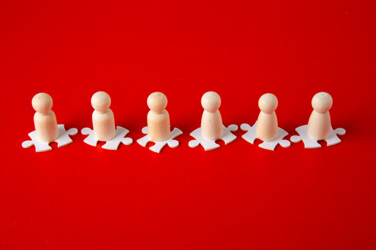 Wooden Figures On Puzzles On Red Background As A Symbol Of Team Building. Organization Group People In Business.