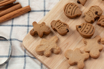 Christmas cookies in many shape on a wooden board, close-up. Christmas homemade gingerbread man and christmas tree cookies on wooden table. Christmas Cookies for children.