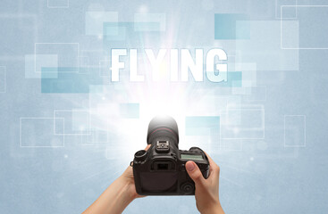 Close-up of a hand holding digital camera with FLYING inscription, traveling concept