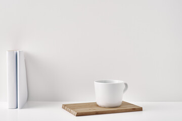 The mug stands on a stack of books on a white background. Natural and eco-friendly materials. Copy space, mock up