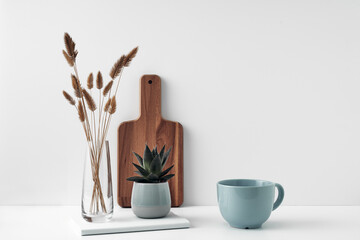 A mug and potted houseplant, a stack of books, a transparent vase and a wooden board. Eco-friendly materials in interior decor, minimalism. Copy space, mock up.